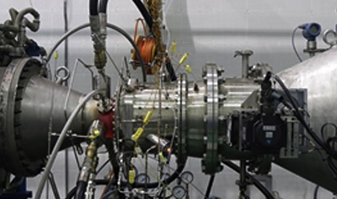 여러 배관과 센서가 연결된 시험 설비에 설치된 제트 엔진