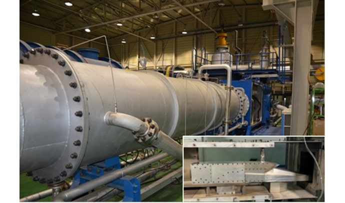 긴 원통형 구조물과 연결된 파이프들이 있는 대형 시험 장치. 오른쪽 아래에는 내부 부품을 보여주는 작은 사진이 삽입되어 있음.