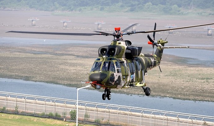 위장무늬로 도색된 한국 육군 헬리콥터가 강가 위를 저공비행하는 모습