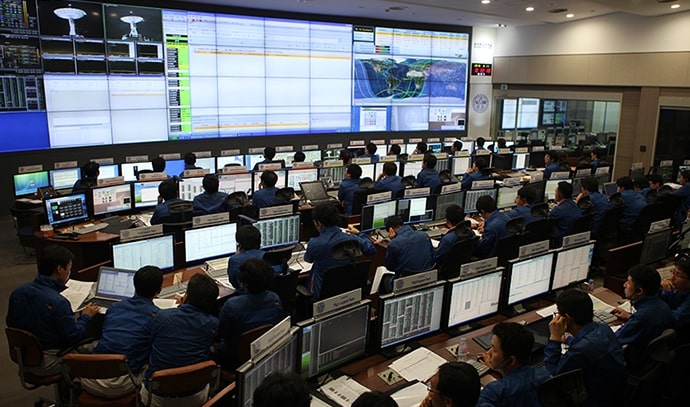 대형 화면이 설치된 통제센터에서 여러 명의 연구원들이 모니터 앞에 앉아 위성 데이터를 실시간으로 관측하고 있는 모습.